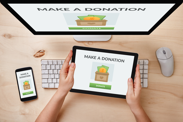 Donation concept on computer, tablet and smartphone screen over wooden table. Top view of responsive devices.